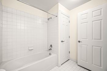 A white bathroom with a tub and two doors.